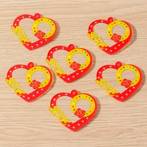Detail view of heart-shaped DIY pendants with LOVE text and rose pattern on wood background