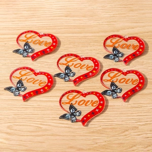 Detailed view of red acrylic heart charms with Love text and butterfly motifs