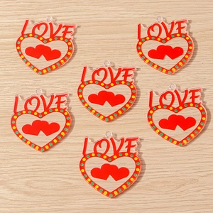 Macro detail of acrylic red heart charm with LOVE text and colorful dot accents for DIY