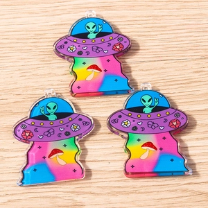 Macro detail of three colorful acrylic UFO and alien charms for DIY jewelry making