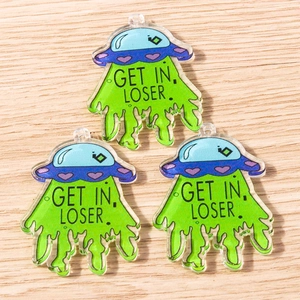 Detail of green acrylic UFO pendants with Get In Loser text on a wood background