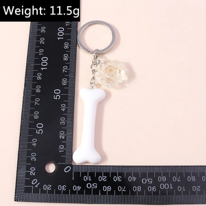 Detailed view of resin flower and bone keychain charm with weight and scale reference