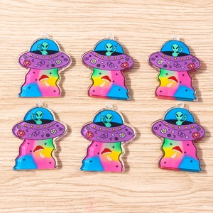 Detailed view of colorful alien UFO acrylic pendants on a light wood background