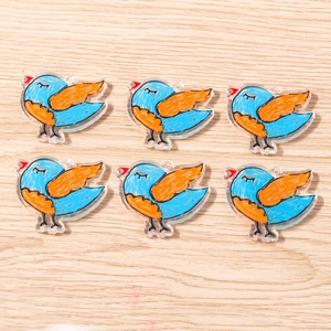 Detail of 6 sky-blue acrylic bird charms with orange wings on a wood background