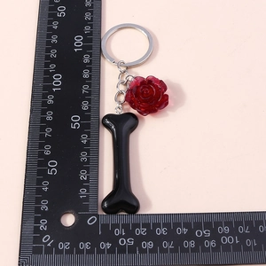Detail view of fashion keychain with black bone and red rose pendant showing size on ruler