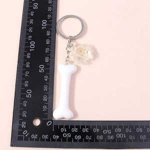 Detailed view of bone-shaped keychain with yellow rose pendant and scale measurements
