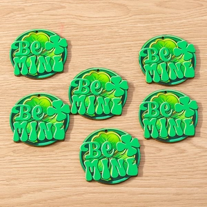 Detailed view of Be Mine shamrock charms with a wooden texture for DIY St. Patrick's Day
