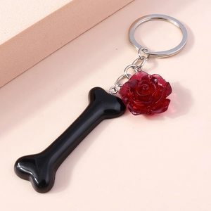 Detail of glossy black bone and dark red resin rose pendants on a silver metal keychain