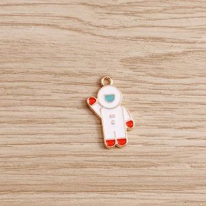 Macro detail of white enamel astronaut pendant with gold metal edges and hanging ring
