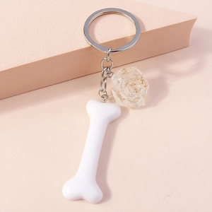 Detail of creative white bone keychain with a transparent rose and gold leaf charm