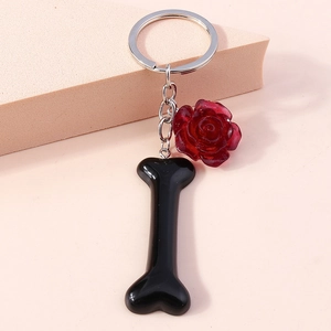 Detailed view of a metal keyring featuring a red rose and black bone pendant
