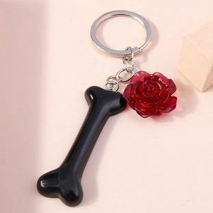 Detail shot of a black bone pendant and dark red resin rose on a silver keychain