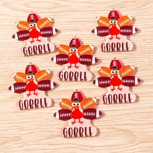Detail of 6 acrylic Thanksgiving turkey and football charms with GOBBLE text on wood background