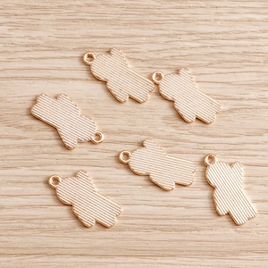 Set of 6 gold-plated bear-shaped pendants with brushed metal texture on a wooden background