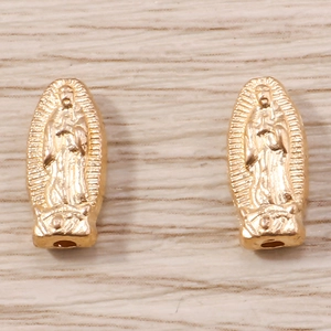 Dettaglio di ciondoli religiosi ovali dorati con rilievo della Vergine di Guadalupe