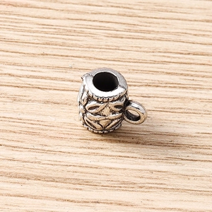 Macro shot of silver cup-shaped charm with vintage floral engraving and center hole