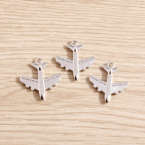 Colgantes de avión plateados para kits de joyería DIY sobre fondo de madera clara
