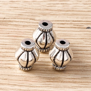 Detail view of retro silver lantern-shaped alloy beads with engraved vertical patterns