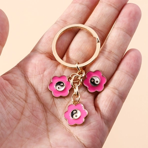 Dettaglio di portachiavi a fiori rosa con simboli Yin Yang tenuti in mano