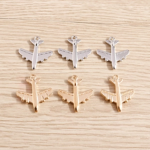 Vista detallada de colgantes de metal con forma de avión en oro y plata para joyería DIY