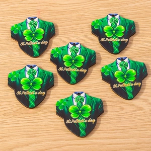 Detail of green suit-shaped wooden St. Patrick's Day shamrock charms on wood background