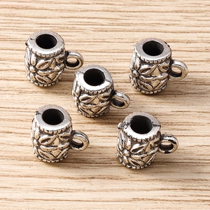 Macro shot of silver retro flower charms on wood surface for DIY jewelry making