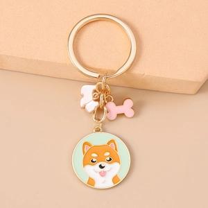 Nahaufnahme eines goldenen Shiba Inu Schlüsselanhängers mit Knochen- und Pfotenanhänger