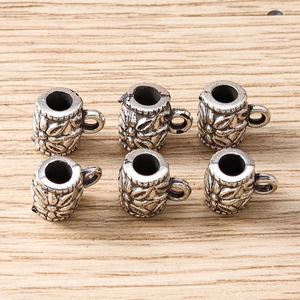 Detailed view of mini cup-shaped silver beads with embossed floral patterns for DIY jewelry