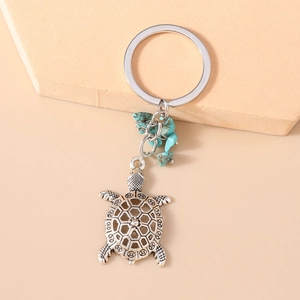 Macro view of vintage silver hollow turtle keychain featuring blue turquoise stones