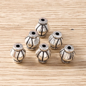 Macro detail of silver lantern-shaped alloy spacer beads with antique finish and vertical stripes