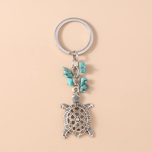 Detail shot of turtle keychain with silver hollow metal shell and green turquoise beads