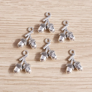 Fünf Vintage Silber Eichel Anhänger auf hellem Holzgrund für DIY Schmuck Bastelarbeiten