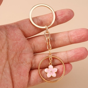Golden cherry blossom keychain with pink flower pendant held in hand for scale