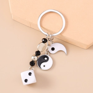 Détail d'un porte-clés tendance avec pendentif yin yang, perles noires et breloque dé
