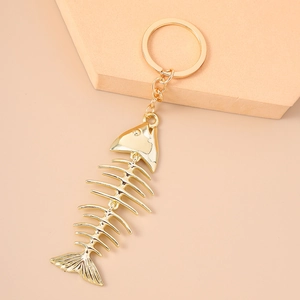 Creative fish bone keychain in mirror gold finish on minimalist display stand