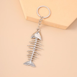 Detailed view of a silver fish bone keychain on a minimalist beige background with props