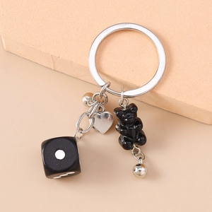 Détail d'un porte-clés avec dé noir, breloque coeur en argent et un petit ours