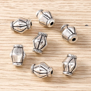 Detailed view of 7 vintage silver alloy lantern beads on a natural wooden background