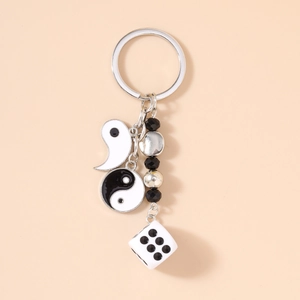 Détail d'un porte-clés argenté avec breloques Yin Yang, perles noires et dé blanc