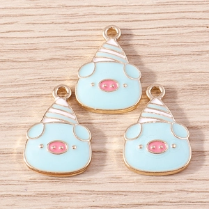 Three cute light blue enamel pig pendants with party hats on a rustic wood background
