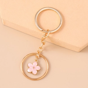 Detail of pink cherry blossom keychain with golden metal ring on soft display base