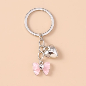 Detailed view of silver heart pendant and pink bow charm on a fashion keychain