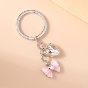 Detail of silver heart charm and pink resin bow pendant on a metal keychain ring