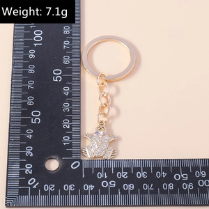 Macro detail of frog keychain with gold alloy finish and sparkling white rhinestone inlay