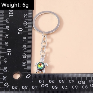 Detailed view of silver turtle keychain with colorful crystals and measuring ruler