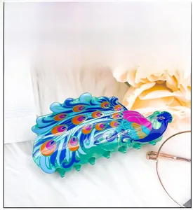 Détail de la pince à cheveux paon colorée avec des plumes vibrantes sur fond doux