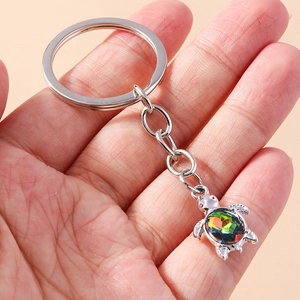 Silver turtle keychain with rainbow crystal pendant held in hand for bag decoration