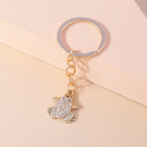 Detailed view of a golden frog keychain encrusted with sparkling white and purple rhinestones