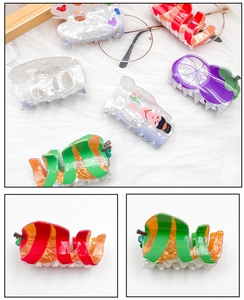 Detail view of acrylic fruit hair claws with mangosteen and apple shaped designs