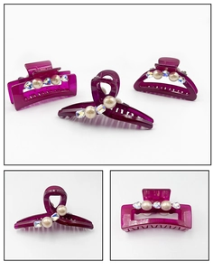 Detailed view of purple hair claws with faux pearls and rhinestones set on white